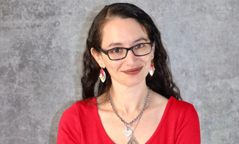 An image of Jessica Puller smiling. She is white with dark wavy hair and a red top.