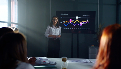 A professor teaches in front a screen with colored graphs on display