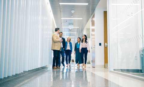 A group of people walk through a hallway as they discuss attentively