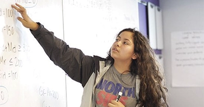 female student showing something on the whiteboard